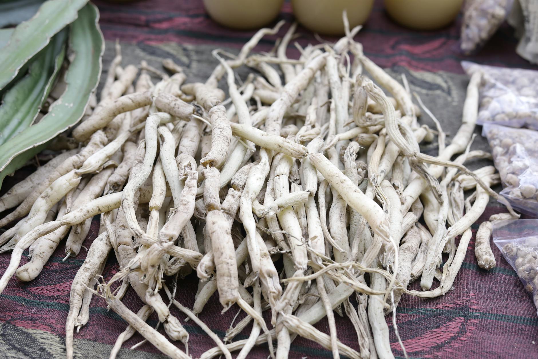 A pile of dried pale ashwagandha root on a rustic surface, the traditional adaptogenic herb studied for sleep and stress