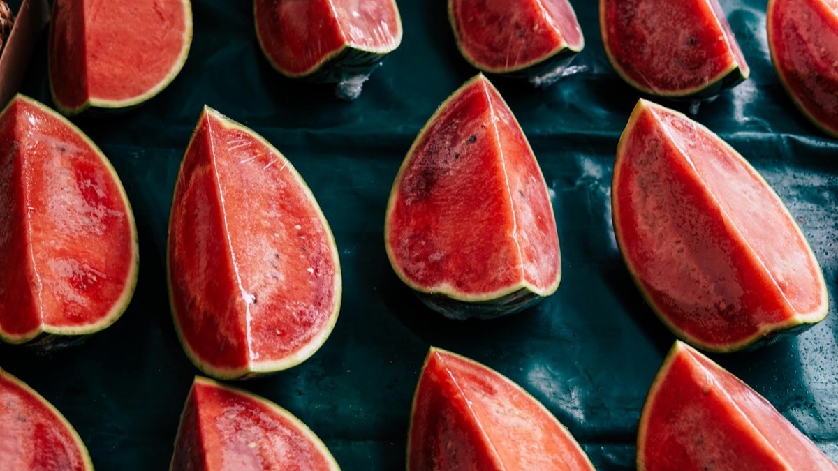 Fresh watermelon cut into wedges and slices on a clean neutral surface in natural light — watermelon is the richest natural dietary source of L-citrulline