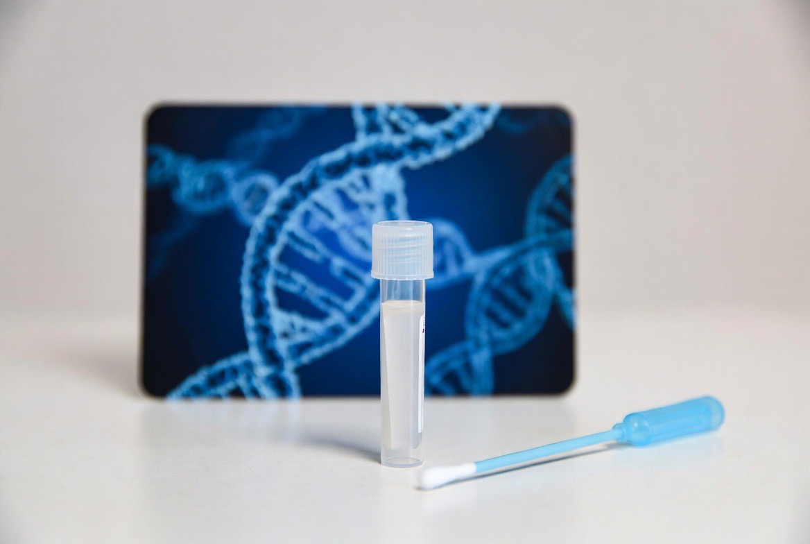 An at-home DNA methylation test kit with a saliva collection tube beside a glowing DNA double-helix, the test kit the clear visual anchor