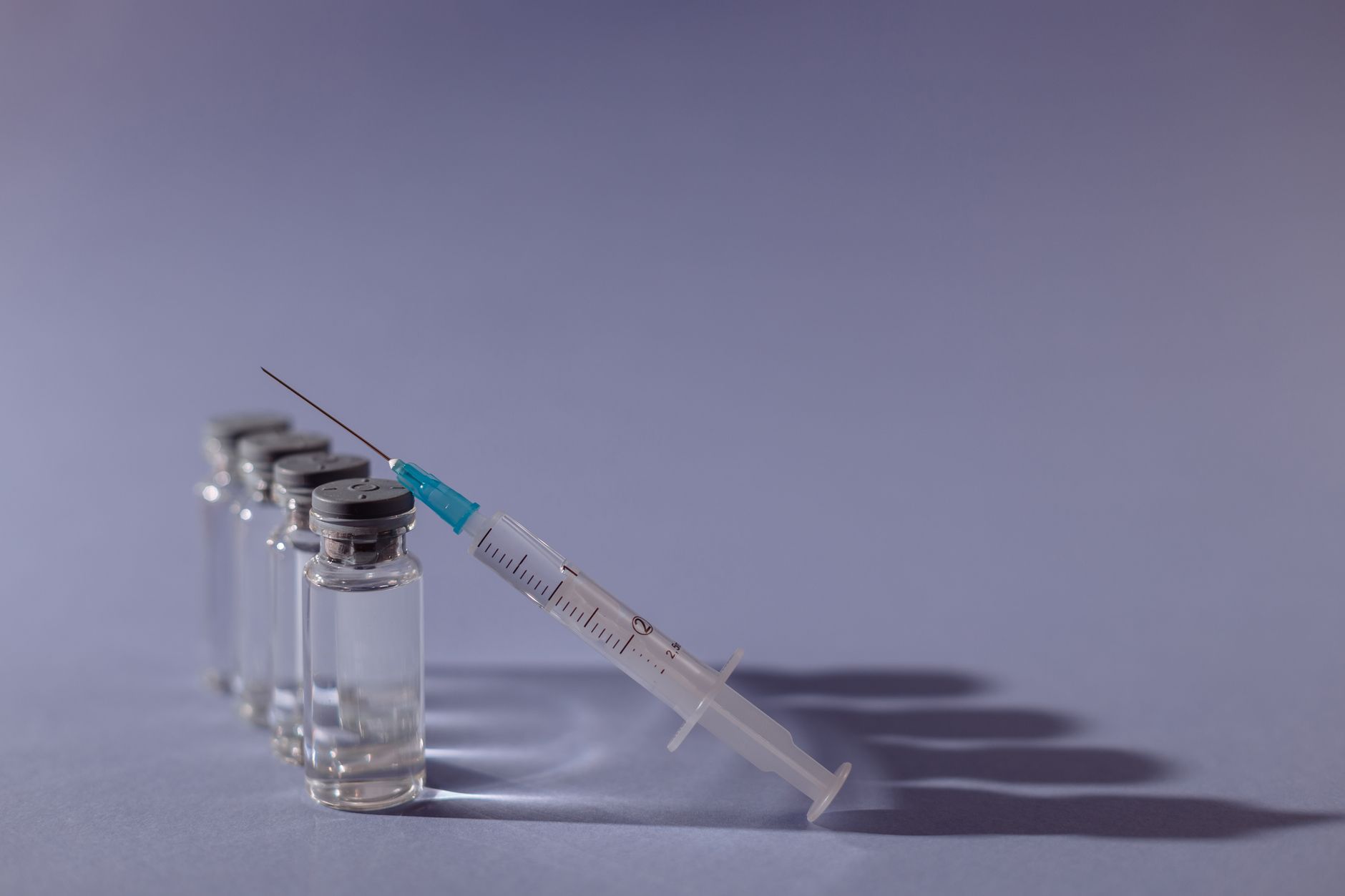 Peptide vials and syringe on an editorial purple background &mdash; representing the GH-releasing peptide class used for lean-mass recovery after GLP-1 cycling