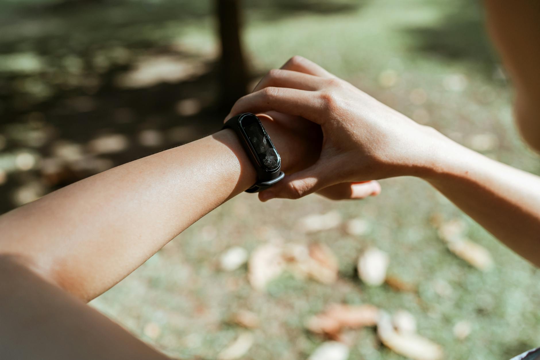 A person checking a wrist-worn fitness tracker in outdoor morning light — the everyday way most people read their nightly HRV and readiness score