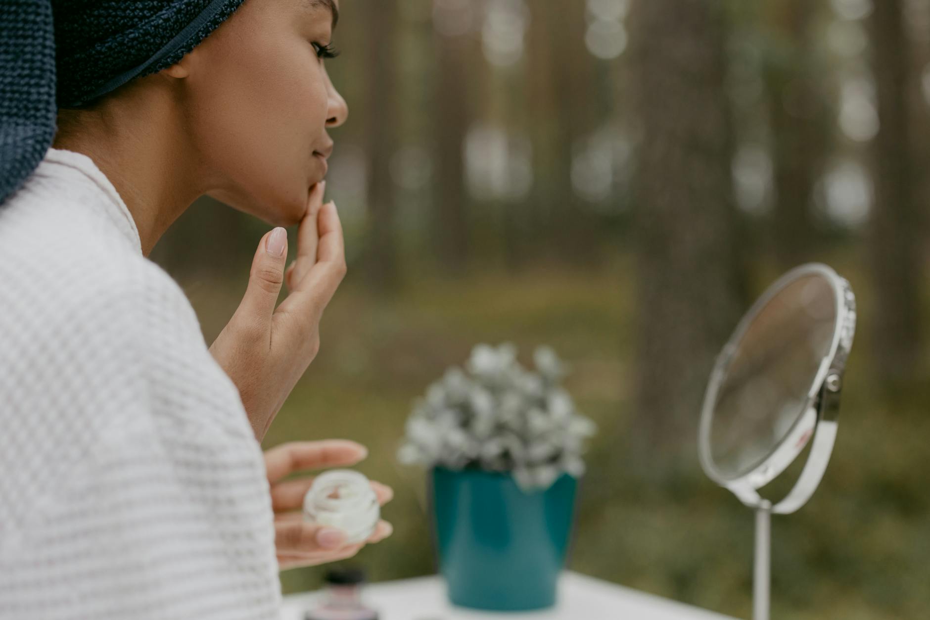A person applying skincare cream to the cheek in soft natural light — niacinamide is one of the few over-the-counter actives with real trial support