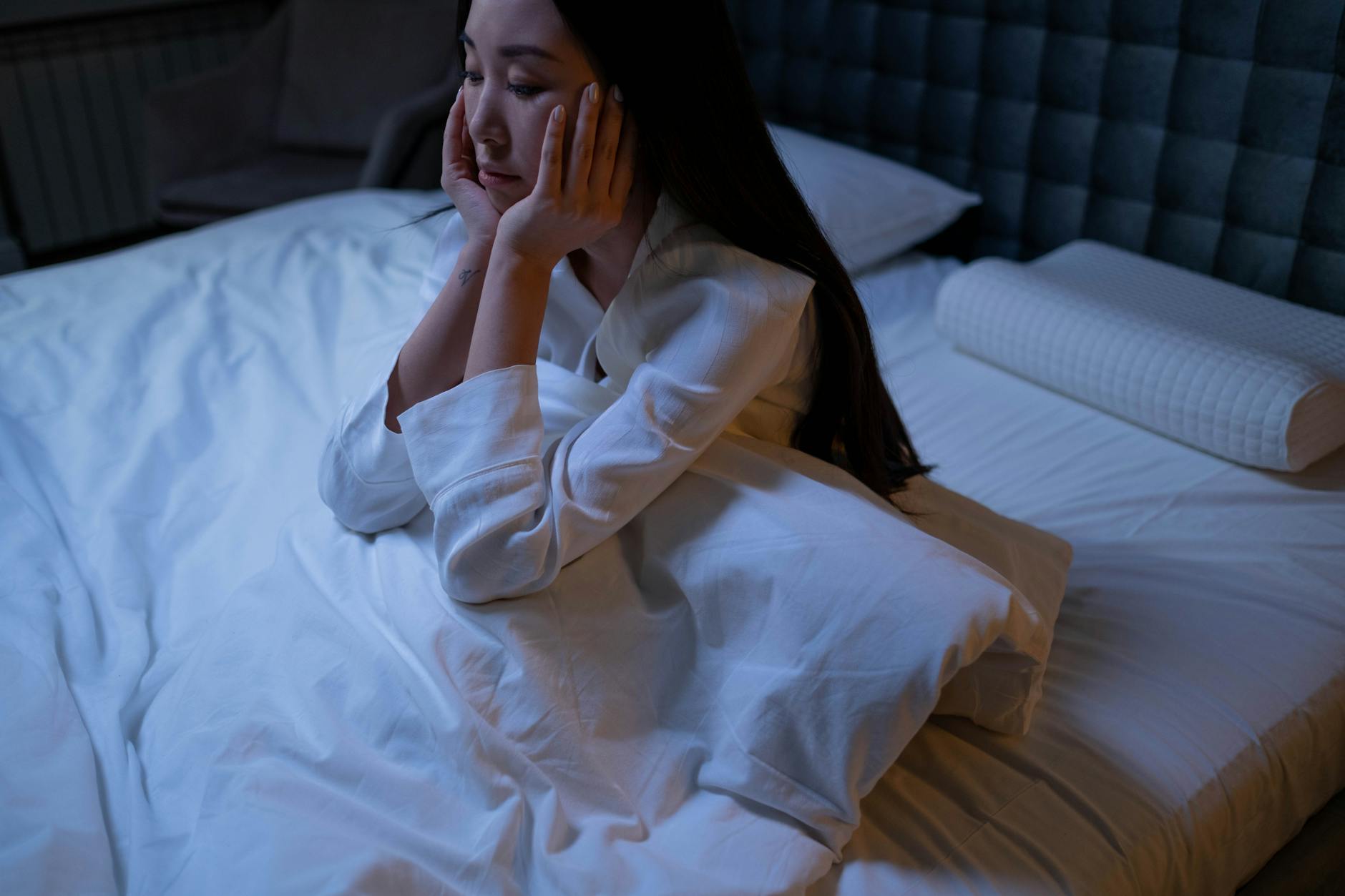 Person sleeping in dark bedroom — chronic sleep deprivation accelerates biological aging