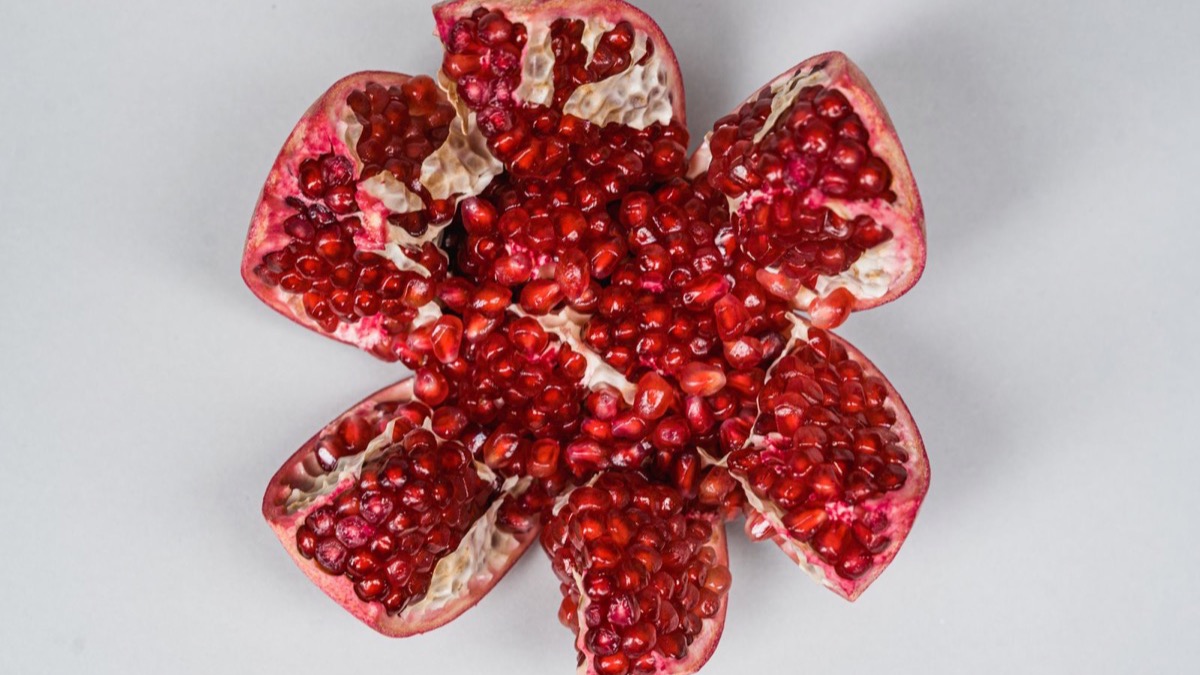 An open pomegranate showing bright red arils — the dietary ellagitannin source the gut converts into Urolithin A for immune-aging support