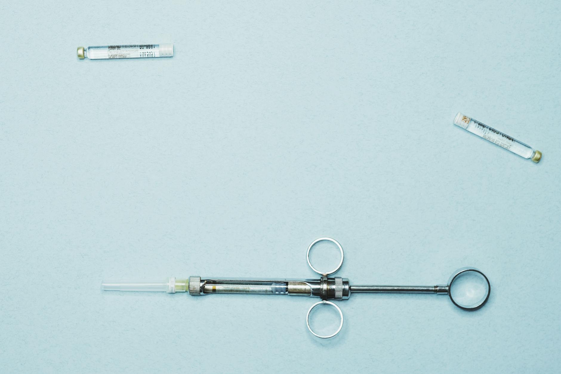 Hormone vial and syringe on clinical surface — testosterone sex hormones